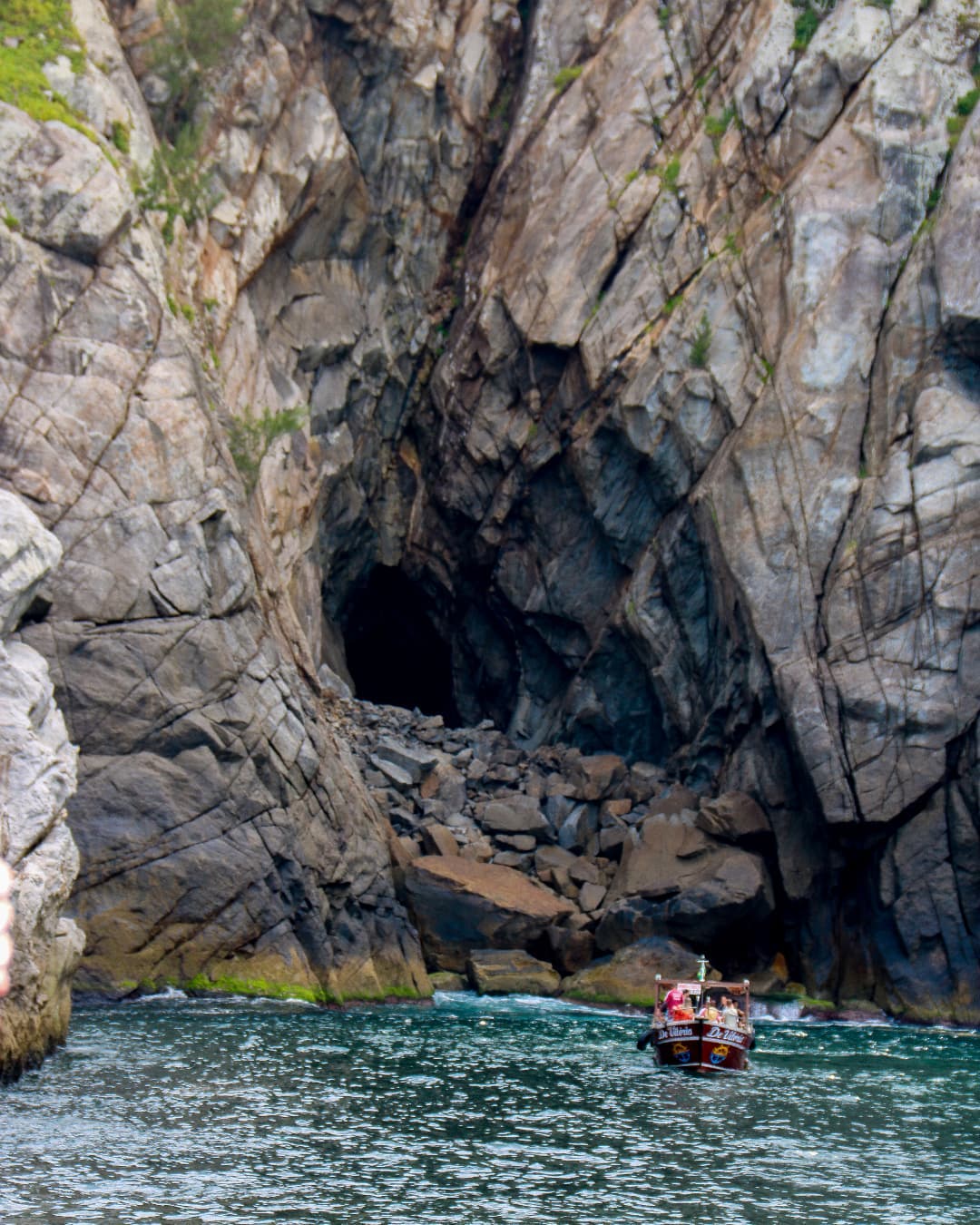 Barco de passeio próximo à entrada de uma gruta em Arraial do Cabo