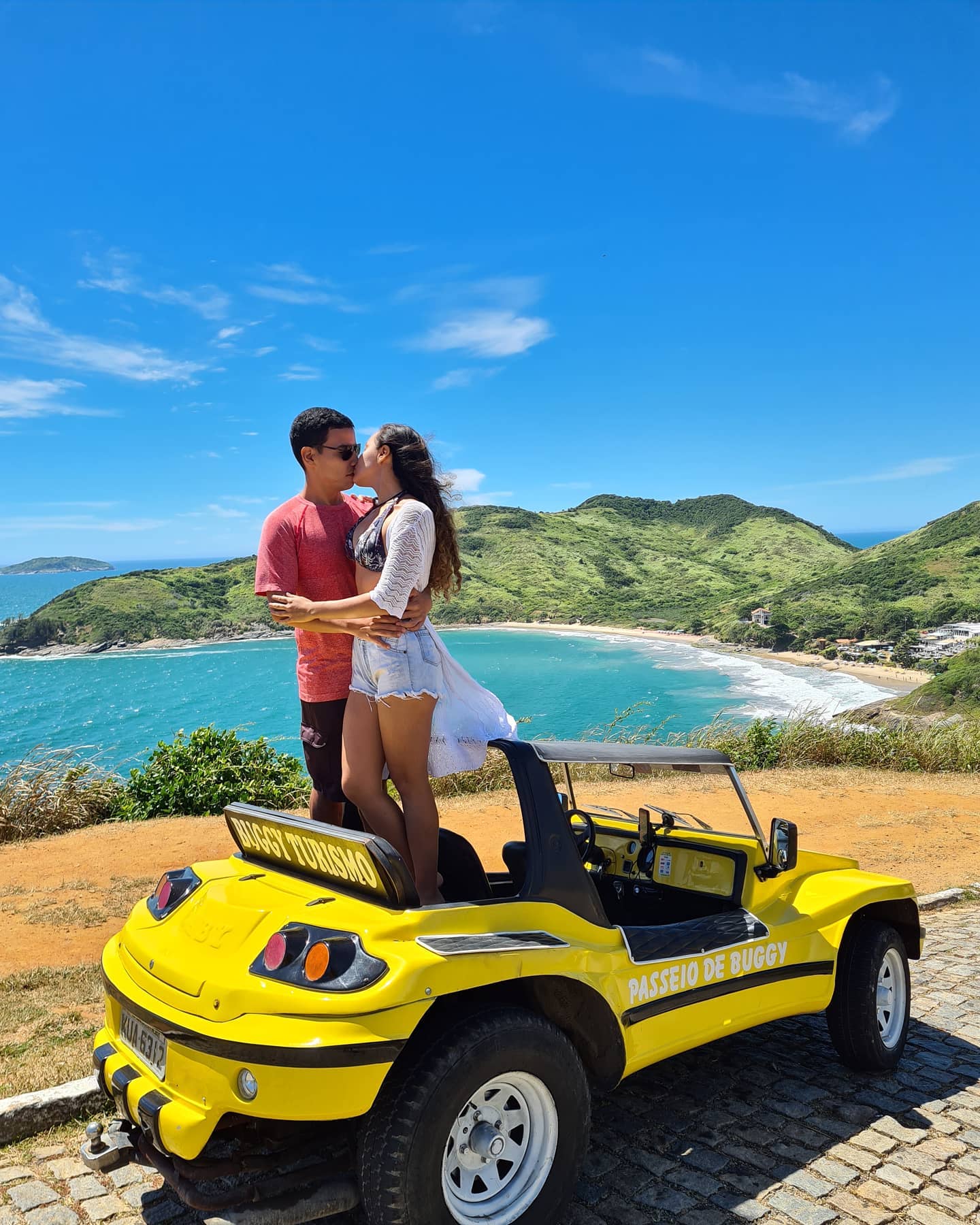 Casal em buggy amarelo com vista para praia em Búzios