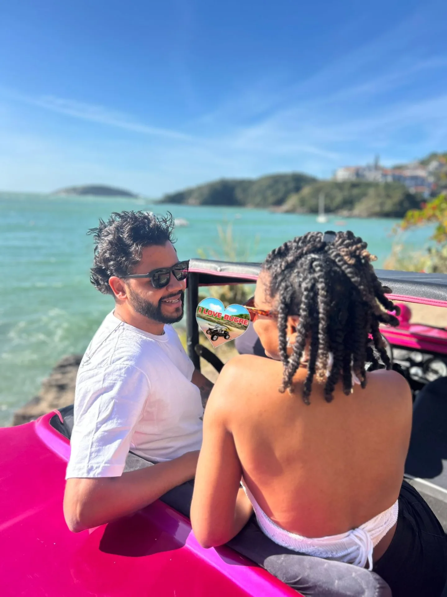 Casal em passeio de buggy rosa com vista para o mar de Búzios