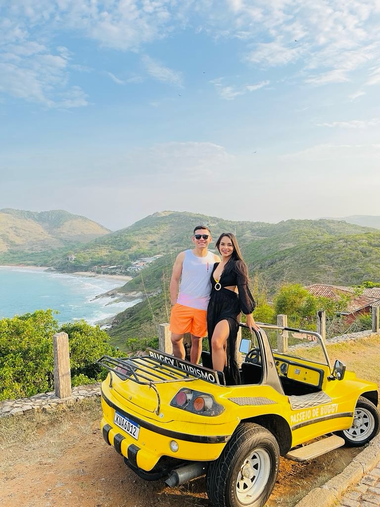 Casal em passeio de buggy amarelo no mirante de Búzios