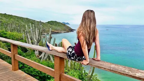 Turista tirando foto do mar azul-turquesa no Mirante de João Fernandes em Búzios