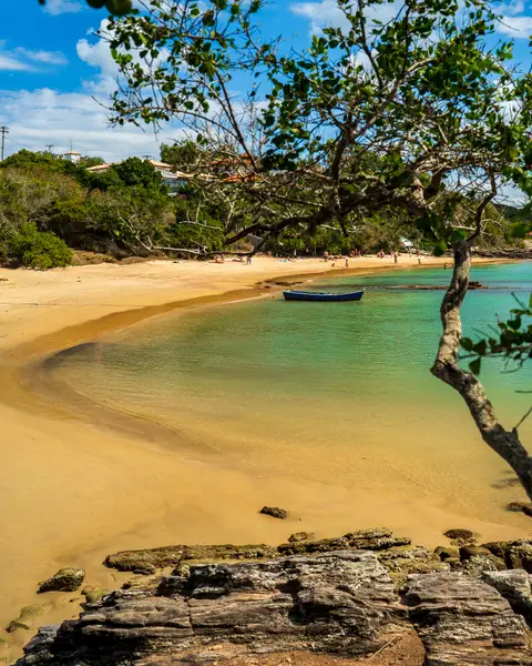 A baía calma em formato de ferradura da Praia da Ferradura em Búzios, com guarda-sóis coloridos e famílias aproveitando a água parada.