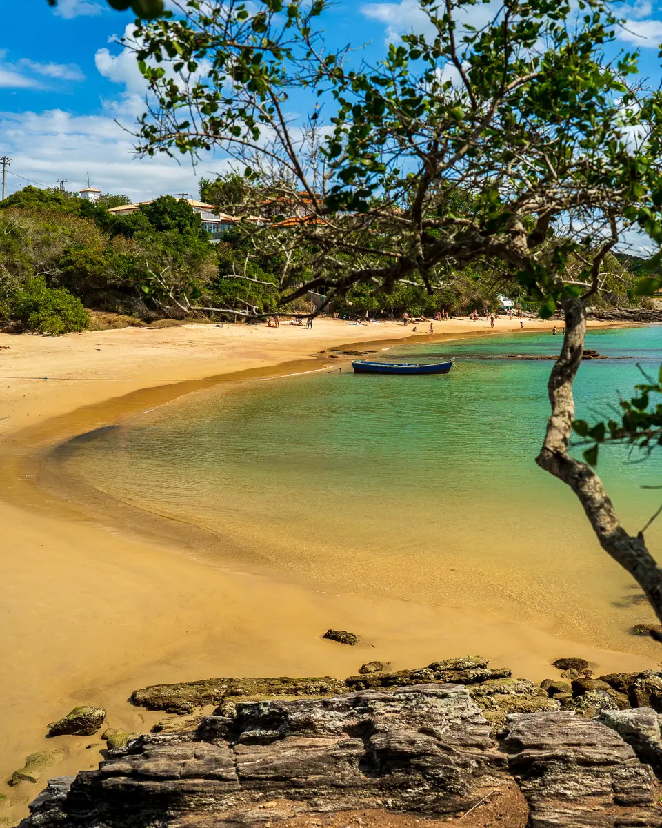 A baía calma em formato de ferradura da Praia da Ferradura em Búzios, com guarda-sóis coloridos e famílias aproveitando a água parada.