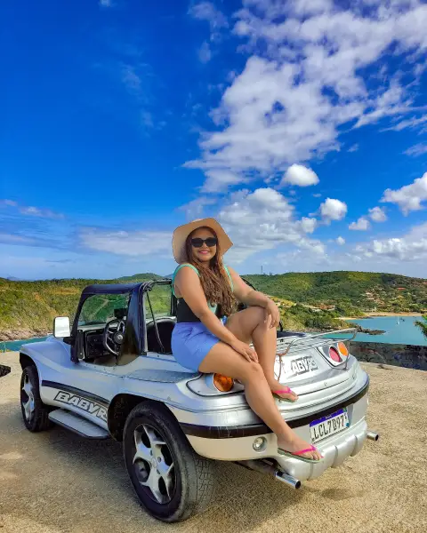Turistas agasalhados levemente aproveitando um dia ensolarado e de céu azul a bordo de um buggy da Buggy Búzios durante o inverno.