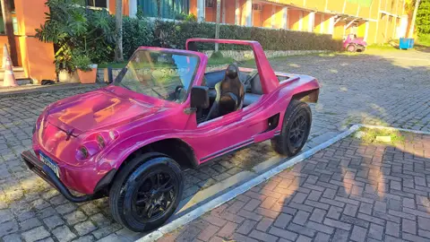 A pink open-air rental buggy parked near the coast in Búzios, offering a fun alternative to traditional car rentals.
