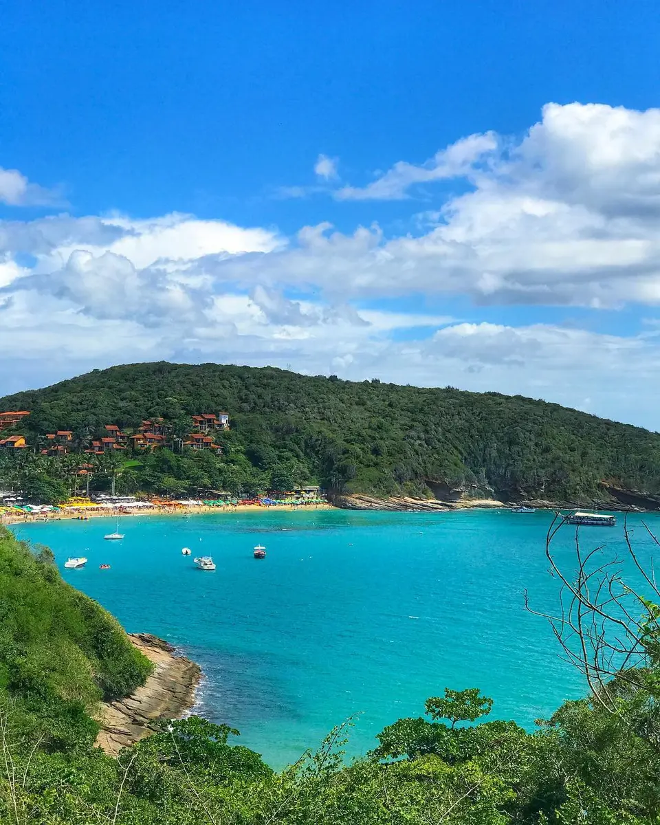 Tourist boat with water slide anchored in turquoise water near Búzios beaches next to an open-top buggy.